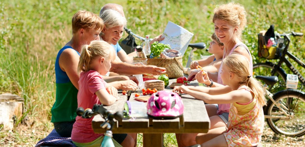 Familie sidder på bænk i naturen